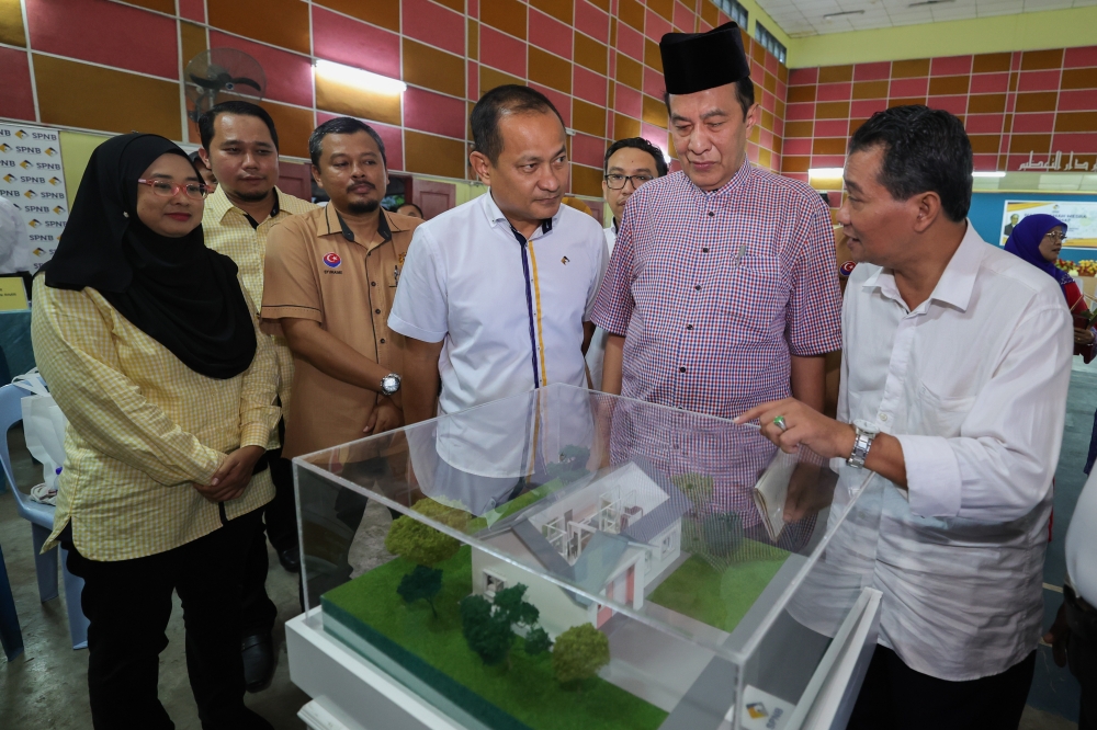 Syarikat Perumahan Negara Bhd chairman Datuk Husam Musa (2nd right) looks at house models at a briefing with second generation settlers at Felda Bukit Ramun in Kulai June 9, 2023. — Bernama pic