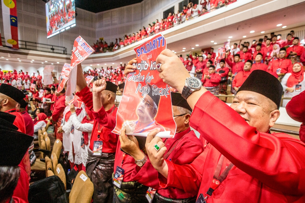 Umno members hold up posters in solidarity with former president Datuk Seri Najib Razak during the 2023 party’s general assembly at the World Trade Centre in Kuala Lumpur June 9, 2023. — Picture by Hari Anggara