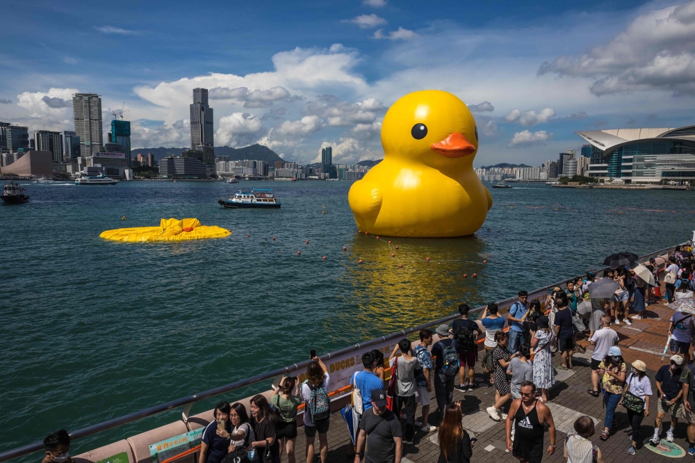 People visit the installation ‘Double Ducks’ by Dutch artist Florentijn Hofman after one of the ducks deflated at Victoria Harbour in Hong Kong on June 10, 2023. — AFP pic