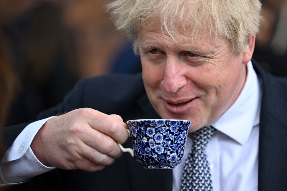 In this file photo taken on May 12, 2022 Britain’s then prime minister Boris Johnson drinks from a cup as he talks with local business leaders after hosting a cabinet away day in Stoke-on-Trent, central England, on May 12, 2022. heaps political pressure on his successor Rishi Sunak. — AFP pic
