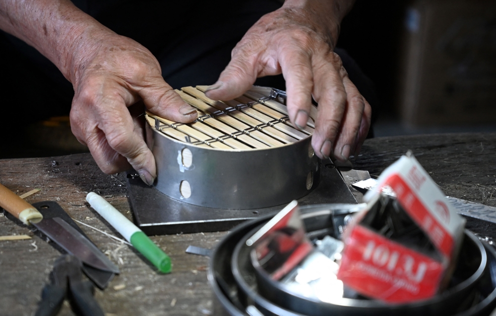 Lui Ming adds steel around the bamboo rim to make his steamers more durable and improve insulation, an innovation he says he pioneered. — AFP pic 
