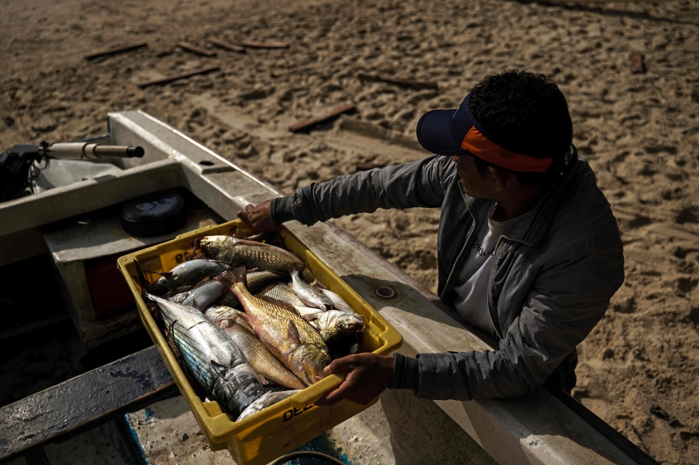 A fisherman collects his catch at the shore of Copacabana Beach in Rio de Janeiro, Brazil on May 23, 2023. — AFP pic