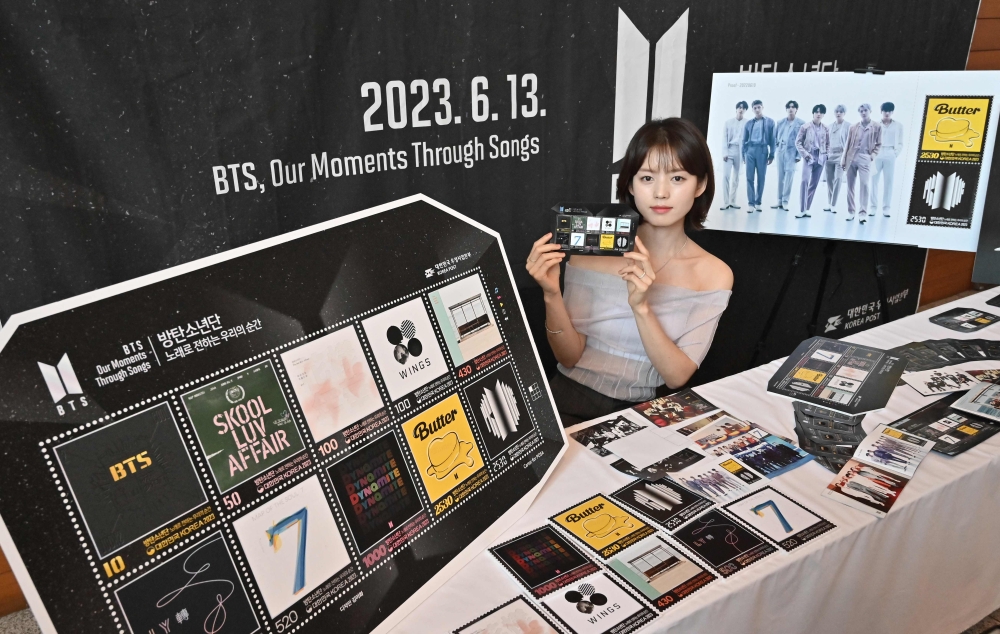 A model shows the BTS 10th anniversary postage stamp set at an event at the Seoul Central Post Office. — AFP pic