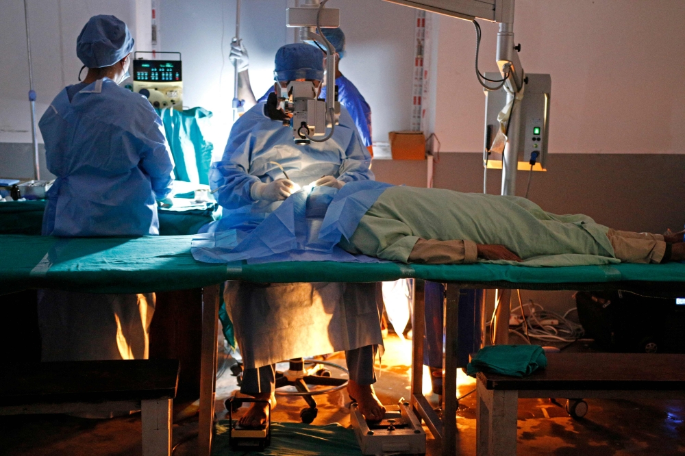 Eye surgeon Sanduk Ruit operates barefoot on a patient at a cataract camp in Tapethok. — AFP pic