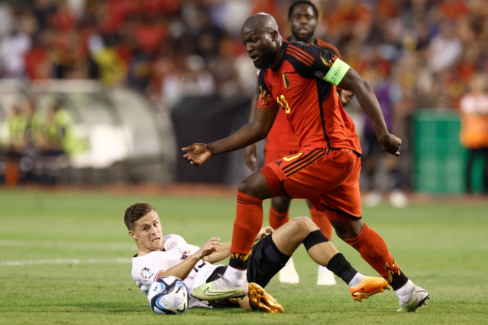 Pemain tengah Austria Christoph Baumgartner (bawah) berebut bola dengan penyerang Belgium Romelu Lukaku semasa perlawanan bola sepak kelayakan UEFA Euro 2024 kumpulan F antara Belgium dan Austria di Stadium King Baudouin di Brussels, pada 18 Jun 2023. — Gambar AFP