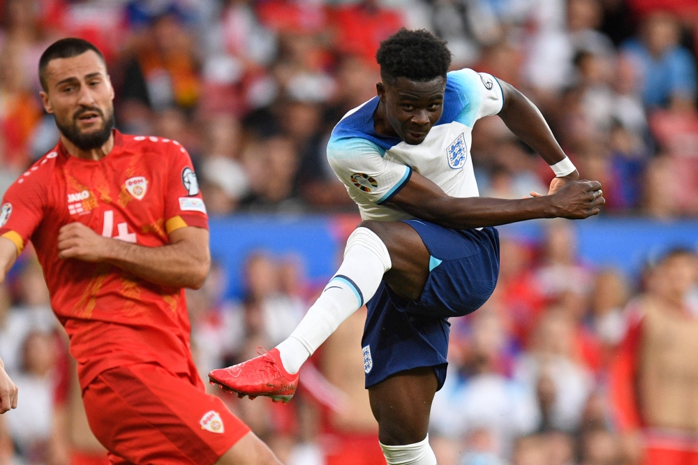 England's midfielder Bukayo Saka (right) shoots past North Macedonia's defender Gjoko Zajkov to score their fourth goal during the UEFA Euro 2024 group C qualification football match between England and North Macedonia at Old Trafford in Manchester June 19, 2023. — AFP pic
