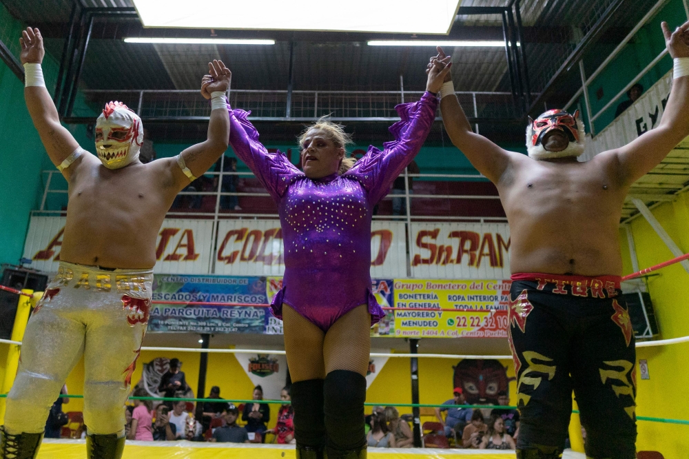 Mexican wrestler Wendy (centre), known as Miss Gaviota, celebrates after winning the main event fight with her wrestling partners Tigre Rojo Jr (right) and Rey Dragon (left) at the San Ramon Coliseum in Puebla, Mexico, on June 18, 2023. — AFP pic