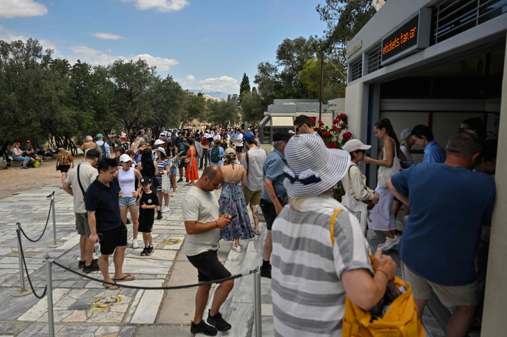 Tourists queue at tickets counter for the Acropolis archaeological site in Athens on June 14, 2023. — AFP pic
