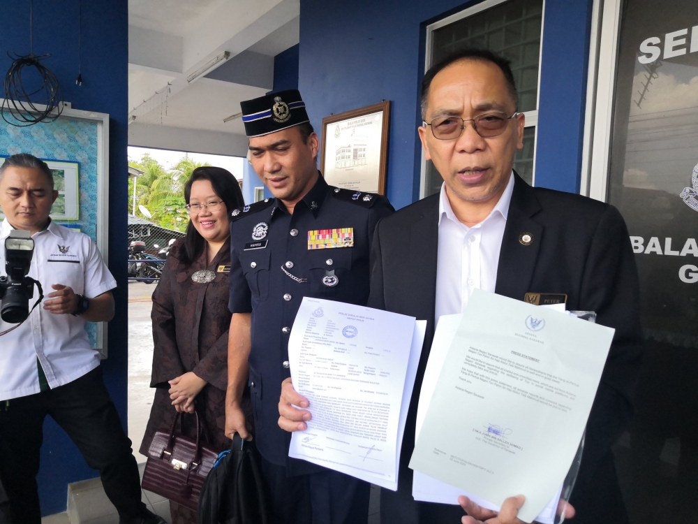 (From right) Peter holds the police report outside the Gita police station accompanied by the Head of State’s aide-de-camp Supt Hamka Mohamad and Astana Negeri Sarawak administrative officer Ratmawati Sabil. — Borneo Post pic
