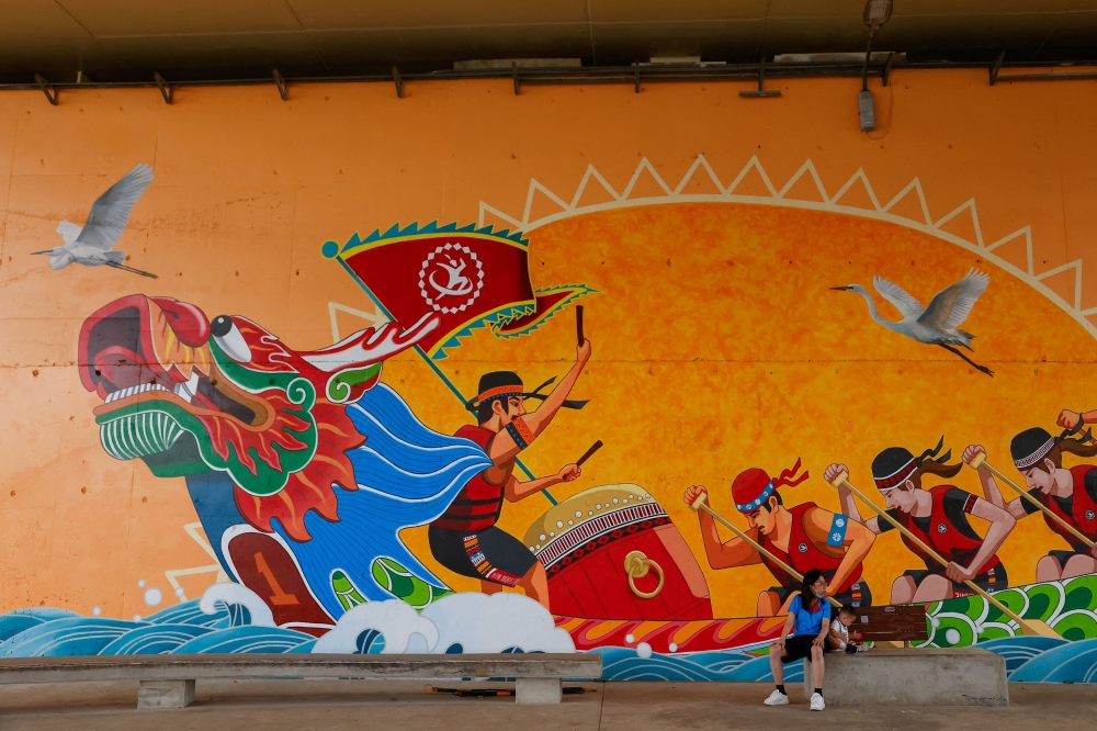 File photo of a family resting in front of a dragon boat race mural painting during the annual Dragon Boat Festival in Taipei, Taiwan June 22, 2023. — Reuters pic
