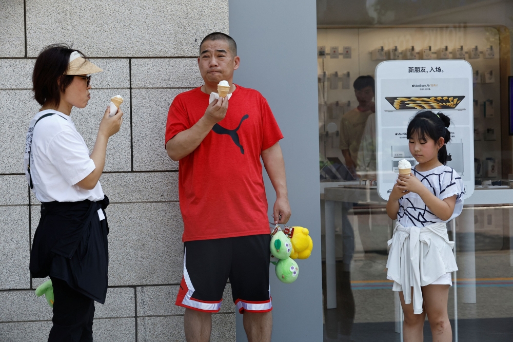 People eat ice cream amid a red alert for heatwave in Beijing, China June 23, 2023. — Reuters pic