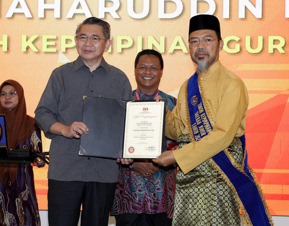 Domestic Trade and Cost of Living Minister Datuk Seri Salahuddin Ayub presents a certificate of appreciation and plaque to the recipient of the Johor Baru District Leadership Award Shaharuddin Saari (right) during the Rahmah ITTV e-Learning launch ceremony in Kempas, Johor Baru June 24, 2023. — Bernama pic
