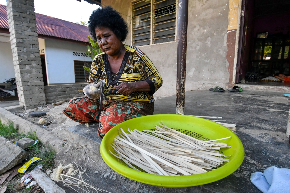 A member of the Mendriq Orang Asli community works on bamboo fibre used to make decorative woven mats, at Kampung Kuala Lah in Gua Musang June 26, 2023. — Bernama pic