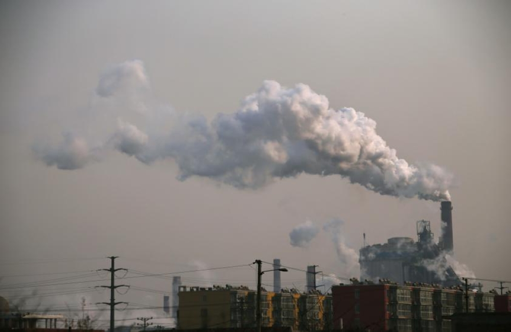 Smoke rises from a chimney of a steel plant next to residential buildings on a hazy day in Fengnan district of Tangshan, Hebei province in this February 18, 2014 file photo. — Reuters pic