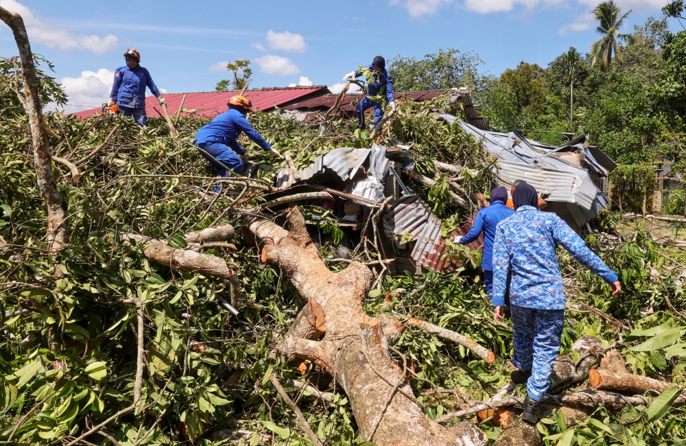 Members of the Malaysian Civil Defence Force Pasir Puteh help to clean up houses hit by the storm yesterday afternoon in Kampung Permatang Sungkai, Kelantan, June 26, 2023. — Bernama pic 