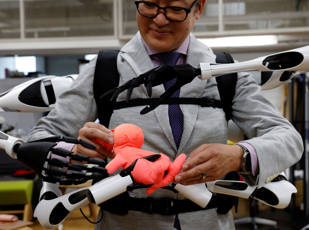 Masahiko Inami dari Universiti Tokyo menunjukkan lengan robot 'Jizai Arms' yang boleh dipakai di makmalnya di Tokyo 22 Jun 2023. — Gambar Reuters