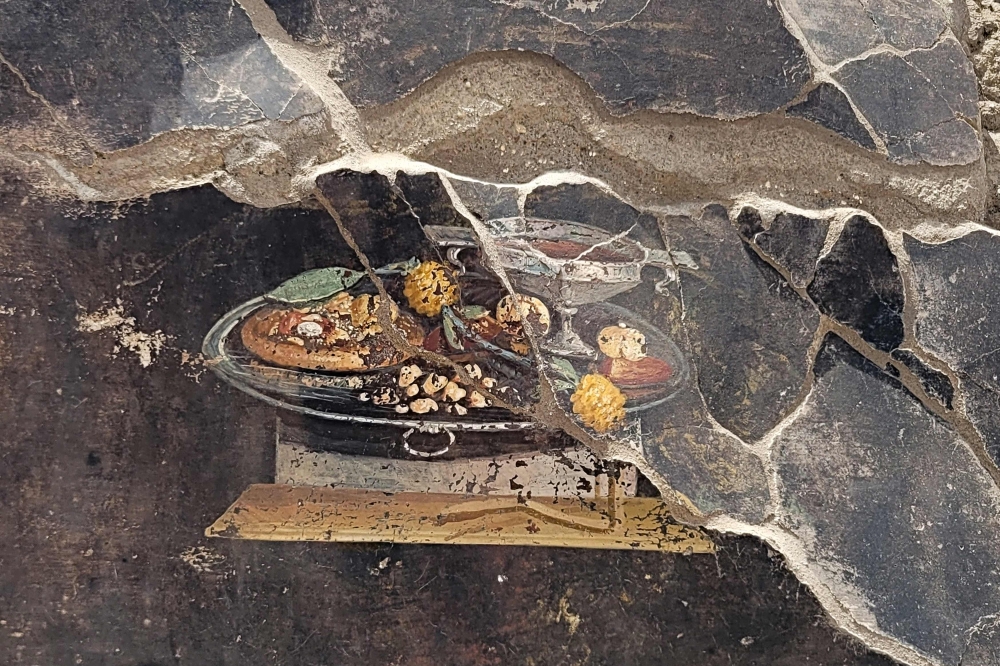 This handout photo taken and released on 25 June by Parco Archeologico di Pompei (Archaeological Park of Pompeii), shows a 2,000-year-old Pompeian painting, a still life, found by the new Regio IX excavations, depicted on the wall of an ancient Pompeian house that could be a distant ancestor of modern pizza. — Parco Archeologico di Pompei press office pic via AFP