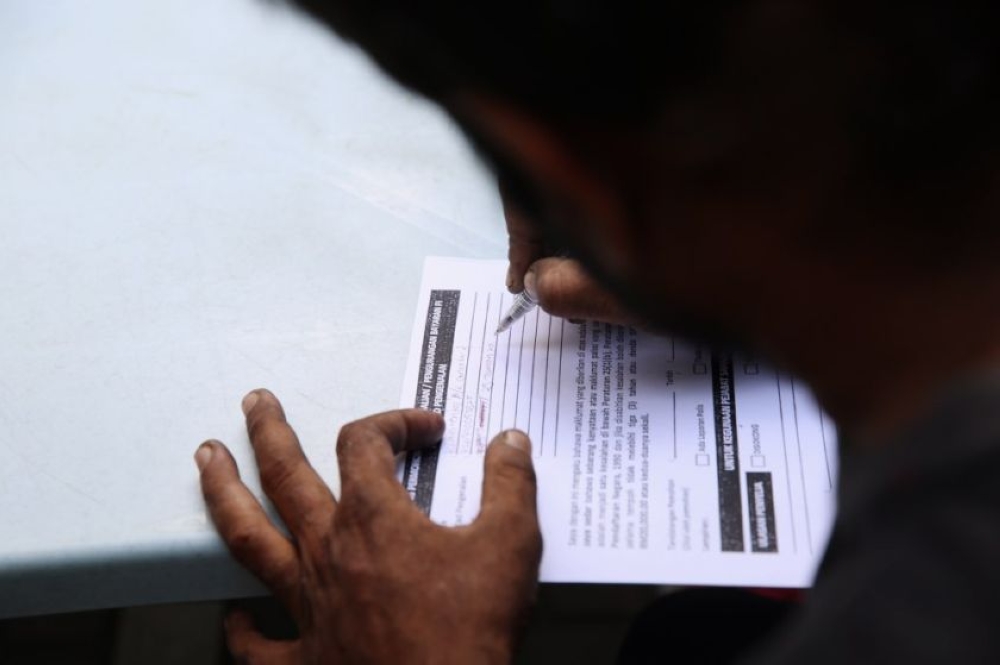 File picture of a person filling up an application form for MyKad before going to the NRD in Kuala Lumpur, July 21, 2014. — Picture by Choo Choy May