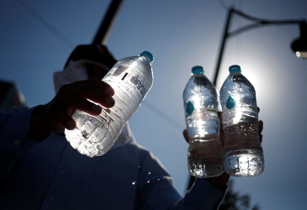 A man sells bottled water during a red traffic light as high temperatures continue, in Monterrey, Mexico June 28, 2023. — Reuters pic