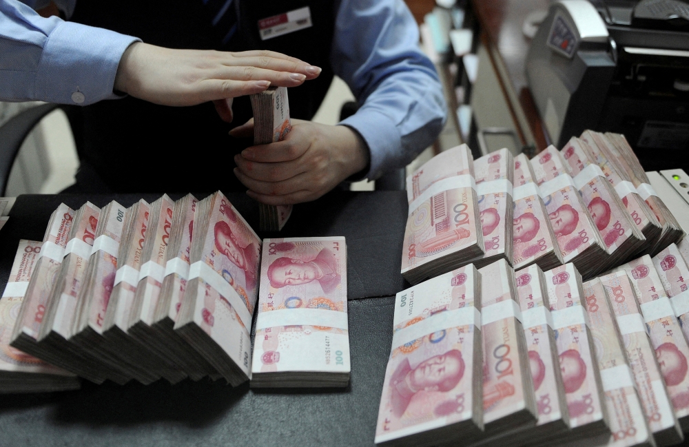 An employee counts 100 Chinese yuan banknotes at a bank in Hefei, Anhui province, January 21, 2013. — Reuters pic