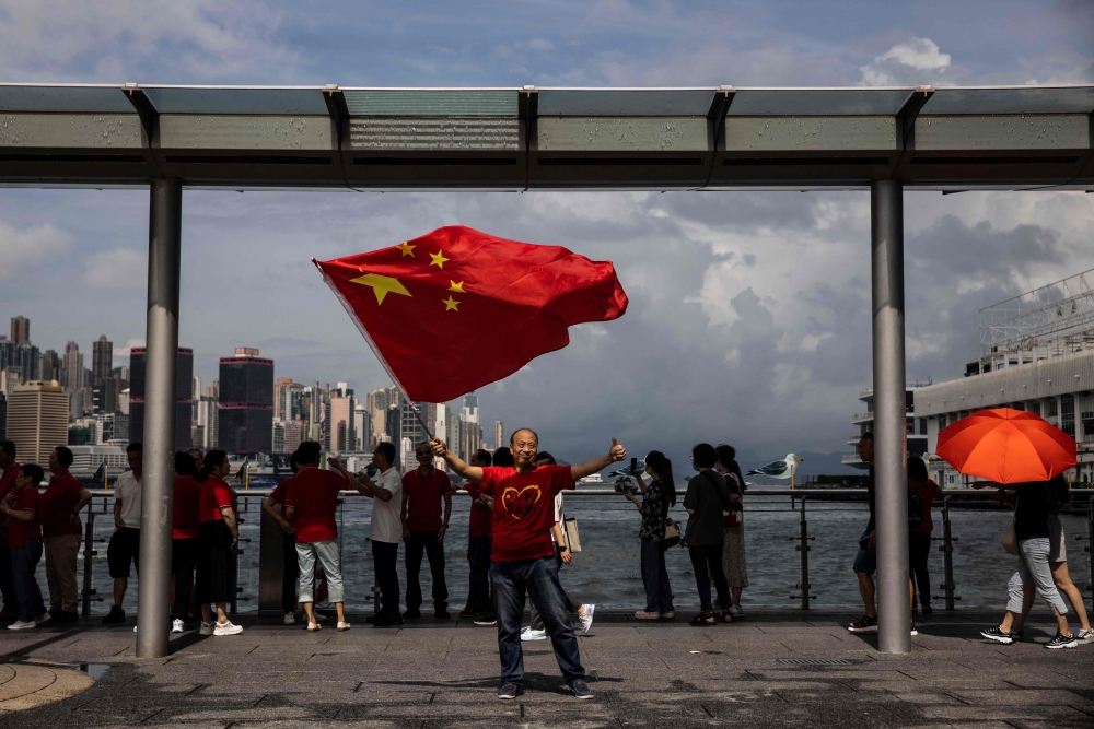 A man waves China's flag on the Tsim Sha Tsui water front in Hong Kong on July 1, 2023, during celebrations marking the 26th anniversary of the city's handover from Britain to China. — AFP pic