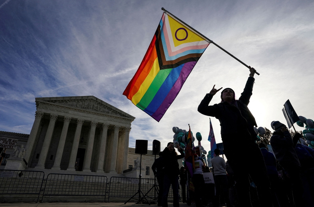 File photo of a protester waving an LGBT rights ‘pride flag’ as activists gather outside the US Supreme Court, where justices were set to hear arguments in a major case pitting LGBT rights against a claim that the constitutional right to free speech exempts artists from anti-discrimination laws in a dispute involving an evangelical Christian web designer who refuses to provide her services for same-sex marriages, in Washington, US, December 5, 2022.— Reuters pic