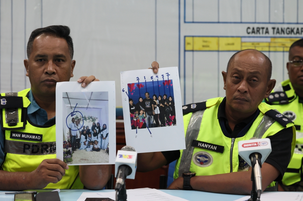 Kemaman district police chief Supt Hanyan Ramlan (right) shows pictures of the 10 victims involved in the water surge incident at Jeram Mawar waterfall, during a press conference in Chukai July 2, 2023. — Bernama pic