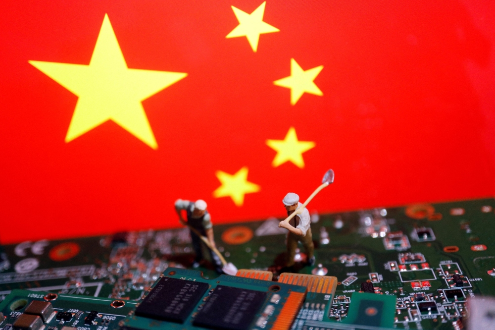 Worker miniatures are placed among the flag of China and printed circuit boards with semiconductor chips, in this illustration picture taken July 5, 2023. — Reuters pic