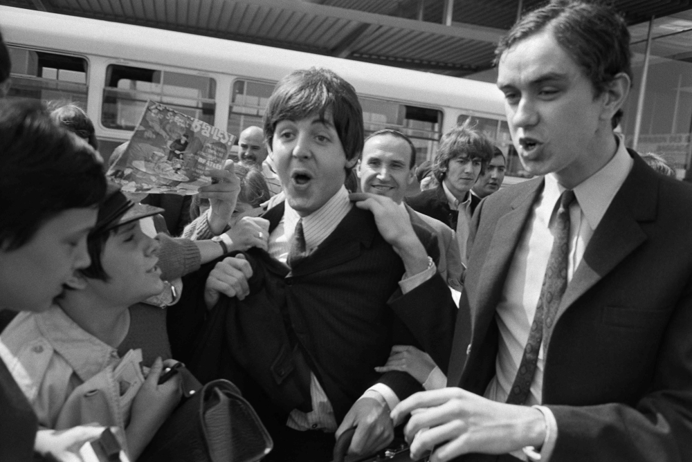 Fans surround Beatles Paul McCartney (centre) and George Harrison (second right) upon their arrival at Orly airport on June 20, 1965, before their concert at the Palais des Sports the same evening. — AFP pic