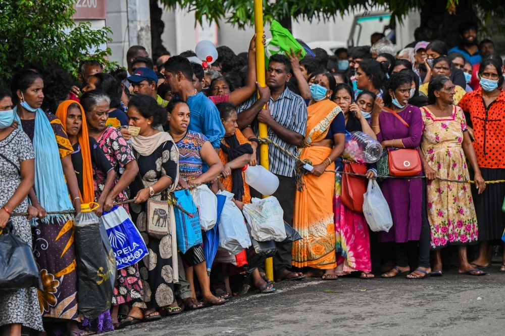 People queue up to buy kerosene for domestic use at a supply station in Colombo on May 26, 2022. — AFP pic