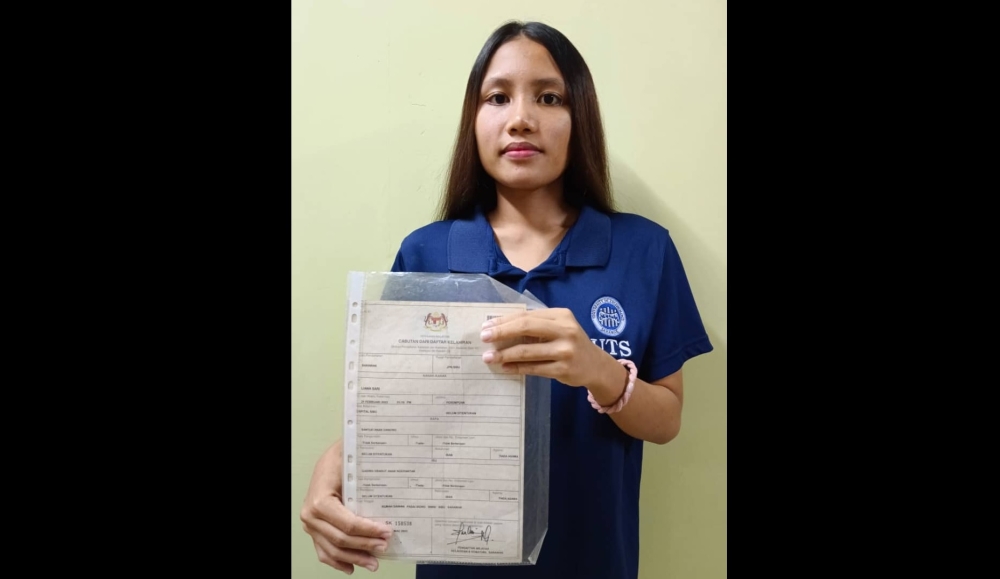 Lianna shows her birth certificate, which is her only form of identification. — Borneo Post pic