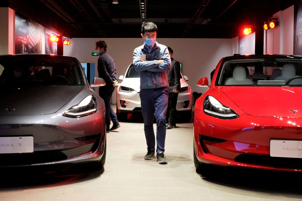 A man walks by Tesla Model 3 sedans and Tesla Model X sport utility vehicle at a new Tesla showroom in Shanghai, China May 8, 2020. — Reuters file pic