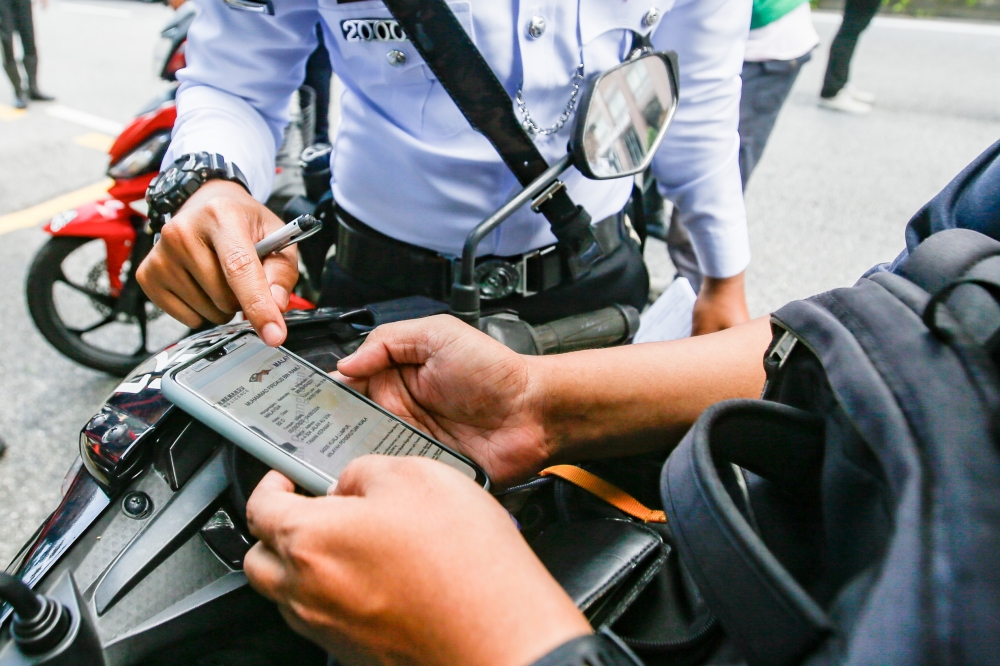 City Traffic Enforcement and Investigation Department personnel checking the driving documents of a motorist during a roadblock in Kuala Lumpur. — Picture by Hari Anggara