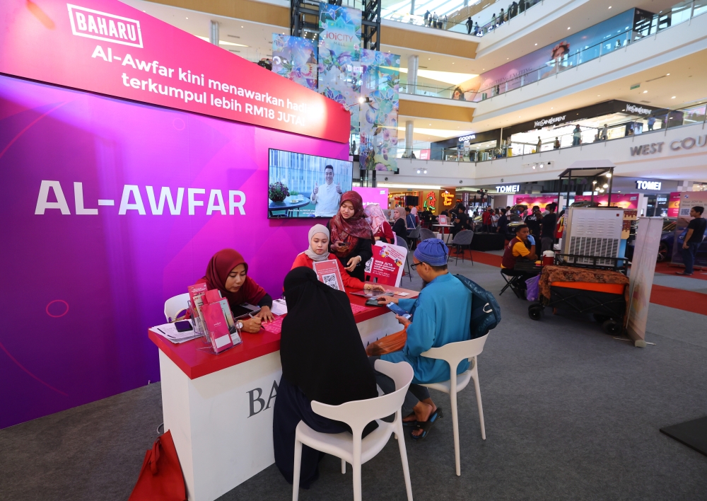 Bank Islam staff speaks to customers registering for new accounts during the launch ceremony of the New Al-Awfar and Al-Awfar account grand prize presentation in Putrajaya July 8, 2023. — Bernama pic