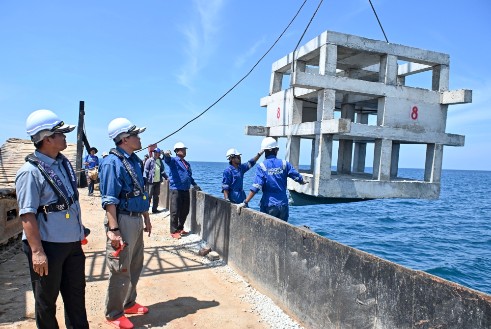Fisheries Department director-general Datuk Adnan Hussain (2nd left) watches workers lowering an artificial reef during a reef sinking programme at the waters of Pulau Kapas, Marang in this file picture taken on June 25, 2023. — Bernama pic