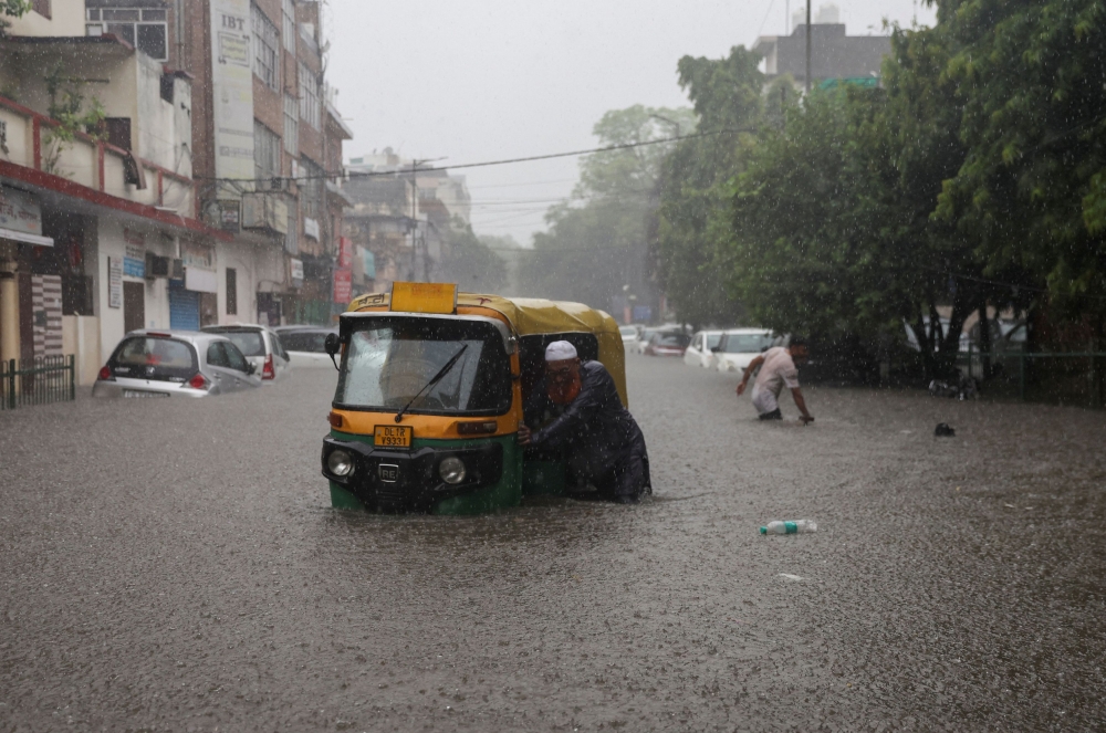 A man pushes his rickshaw in a flooded street after heavy rains in New Delhi, India, July 8, 2023. — Reuters pic