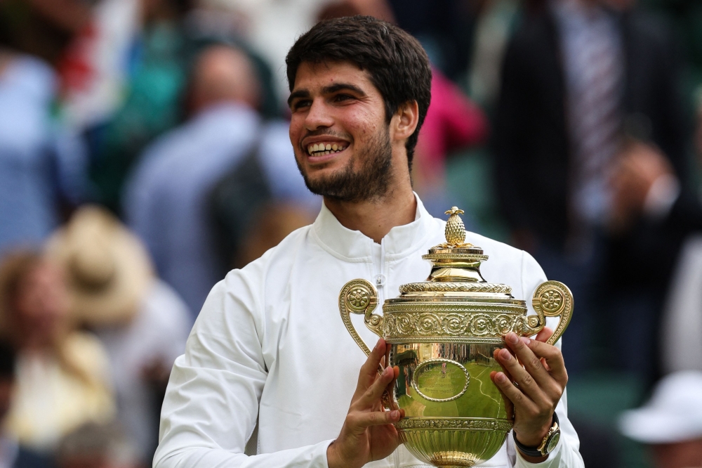 Carlos Alcaraz dari Sepanyol tersenyum sambil memegang trofi pemenang selepas menewaskan pemain Serbia Novak Djokovic semasa perlawanan tenis akhir perseorangan lelaki mereka pada hari terakhir Kejohanan Wimbledon 2023 di Kelab Tenis All England di Wimbledon 16 Julai 2023. — Gambar AFP