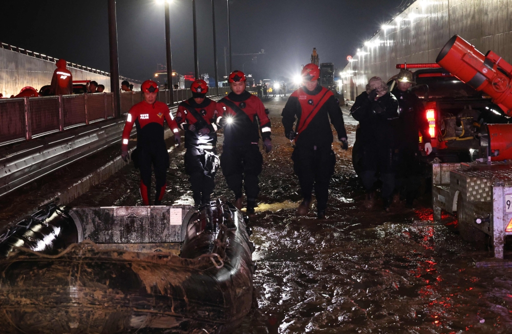 Rescue workers search for missing people along an underground tunnel, where some 15 cars were trapped in floodwaters after heavy rains, in Cheongju early on July 17, 2023. — Picture by Yonhap via AFP