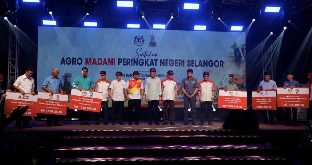 Prime Minister Datuk Seri Anwar Ibrahim (centre) with aid recipients at the Selangor State Level Madani Agro Touch Programme in Sekinchan, Sungai Besar, July 18, 2023. — Bernama pic 