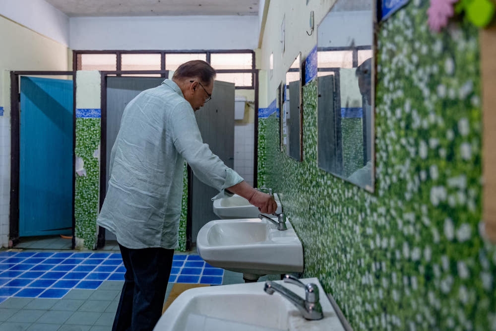 Prime Minister Datuk Seri Anwar Ibrahim checks the condition of faucets in a school bathroom during a spot check on schools in Sungai Besar, July 18, 2023. Last month the prime minister raised the issue of dirty school toilets which he described as a never-ending problem. — Picture from Facebook/Anwar Ibrahim