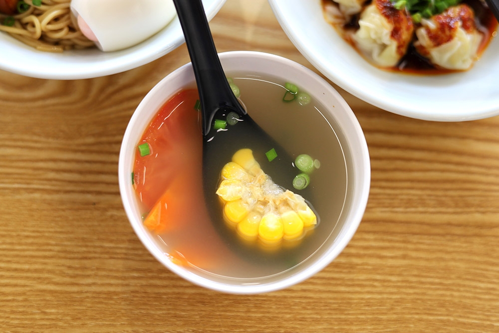 Mee kering dihidangkan dengan sup jernih ala rumah dengan sayur-sayuran dan sepotong jagung rebus.