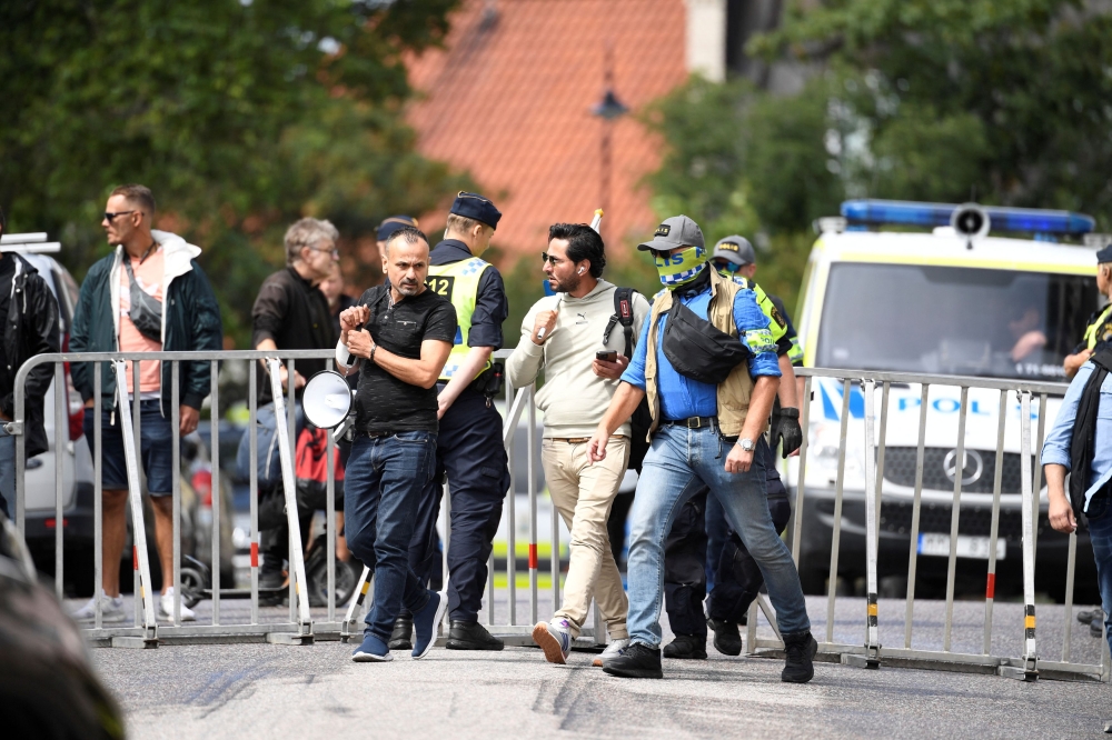 Protestor Salwan Momika, who planned to burn a copy of Koran and the Iraqi flag, is escorted by police to a location outside the Iraqi embassy, in Stockholm. — Reuters pic