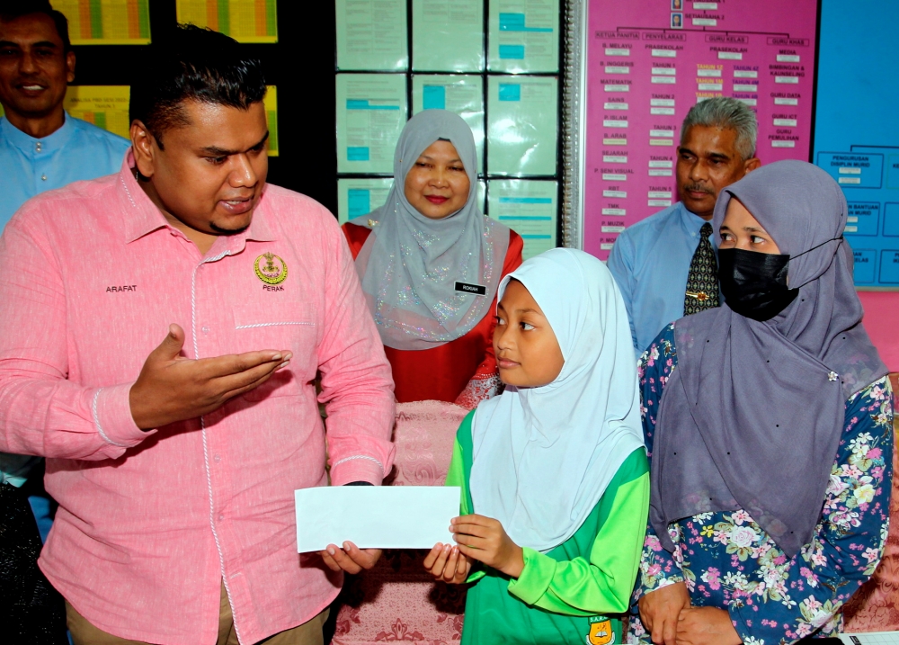 Hulu Kinta assemblyman Muhamad Arafat Varisai Mahamad handing a donation to Nur Alisha Adawiyah Mohd Yusri who was injured when a toilet cistern was dislodged from its mounting and crashed onto her. ― Bernama pic
