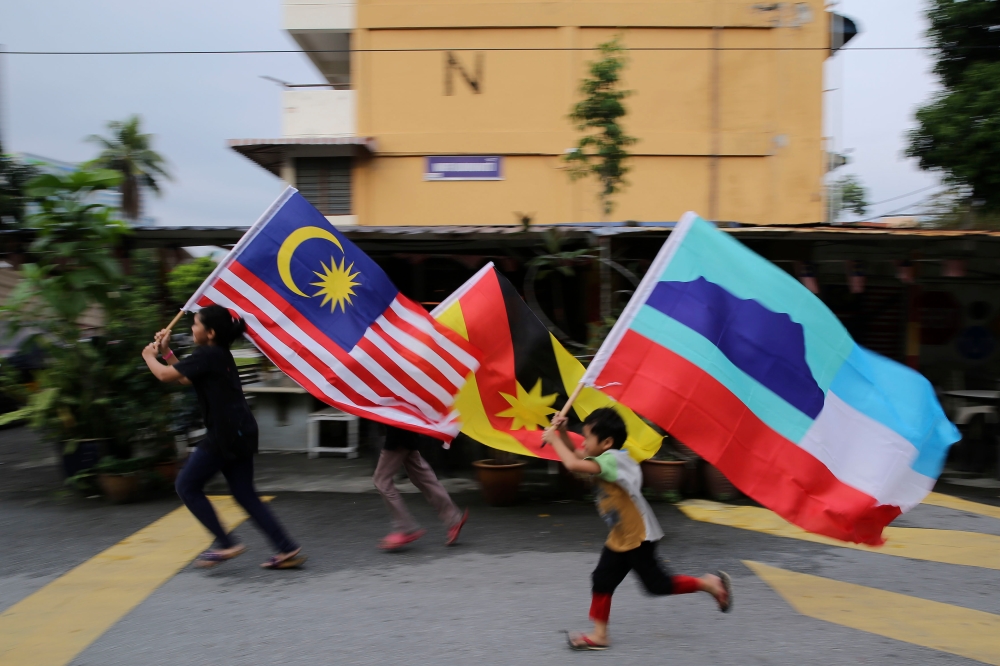 Children holding the Jalur Gemilang, Sarawak and Sabah flags are seen in this file picture. — Picture by Yusof Mat Isa