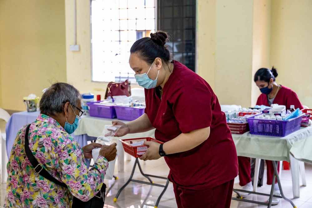 Edeena Marcellena Engel attends to a patient under the Assunta Mobile Clinic at PPR Kampung Baru Air Panas in Kuala Lumpur July 12, 2023. — Picture by Firdaus Latif