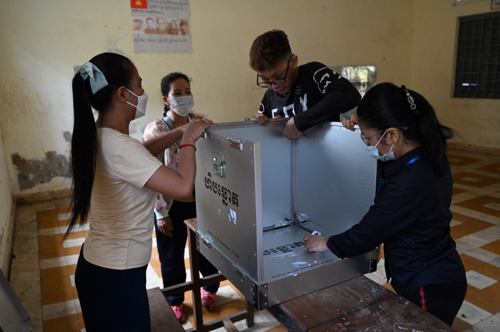 Officials prepare an information poster at a polling station before Sunday’s election, in Phnom Penh on July 22, 2023. ― AFP pic