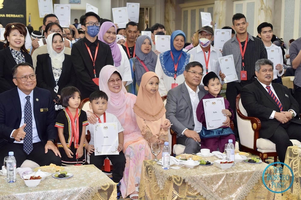 Saifuddin (seated second right) and Fatimah (seated second left) pose with officials and some of the recipients of citizenship approval letters. Seated at left is State Secretary Datuk Amar Mohamad Abu Bakar Marzuki.  — Borneo Post Online pic