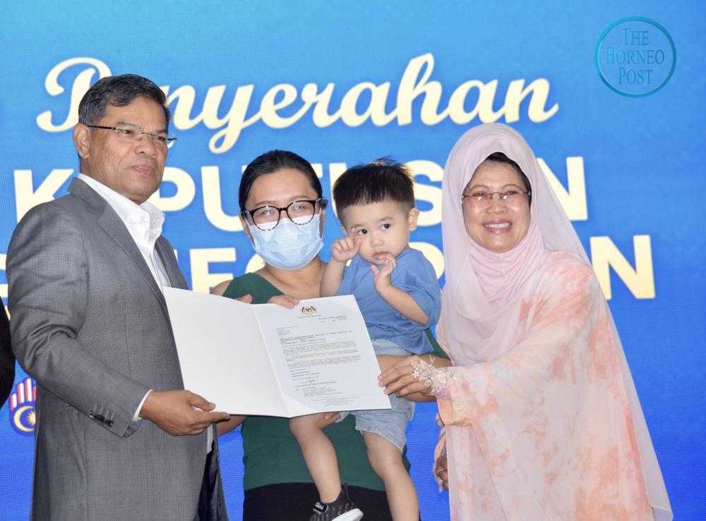 Saifuddin and Fatimah jointly present a citizenship approval letter to a recipient. — Borneo Post Online pic