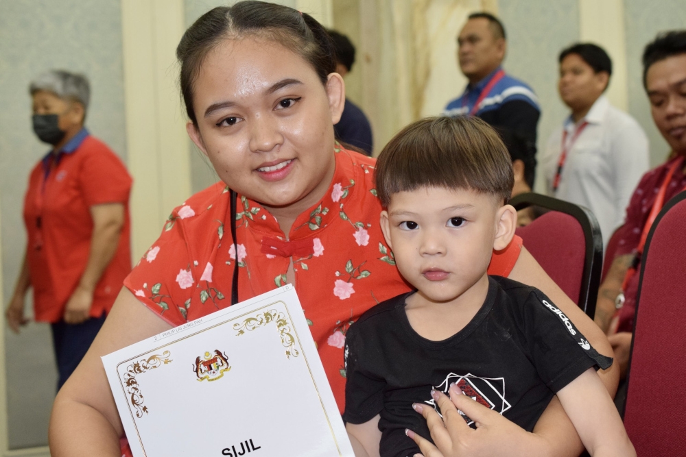 Christina hugs Philip (right) and proudly shows his citizenship approval letter. — Borneo Post pic