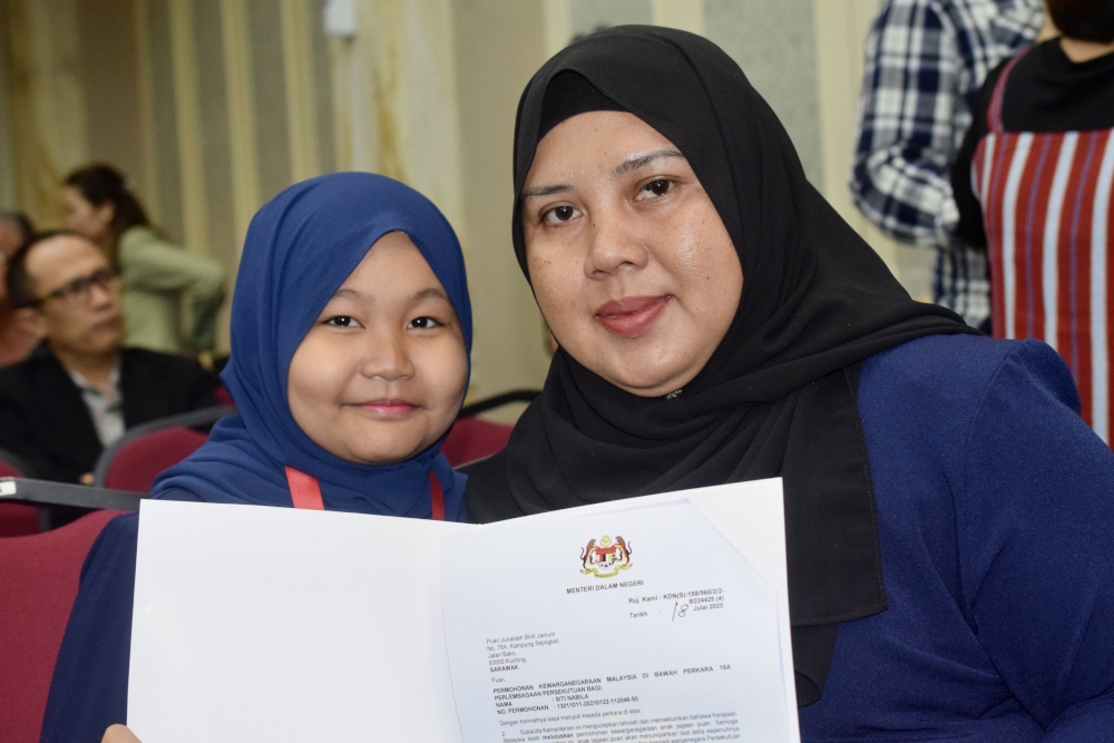 Siti Nabila and her adoptive mother Junaidah Jamuni express gratitude after Siti received her citizenship today. — Borneo Post pic 
